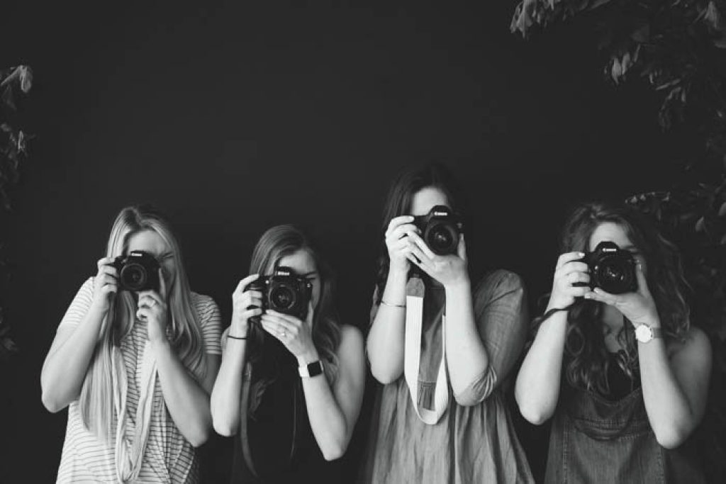 عکس سیاه و سفید از چهار عکاس مبتدی که دوربین های DSLR در دست دارند