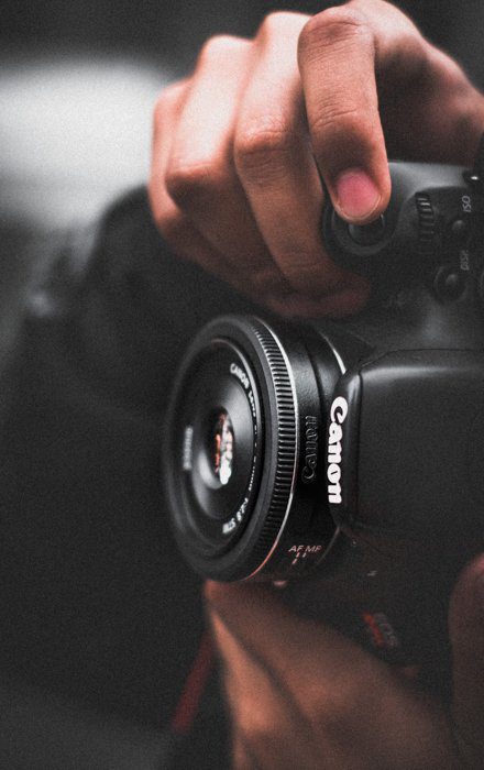 تصویری نزدیک از مردی که با دوربین DSLR کانن عکس می گیرد