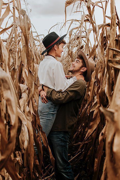 ژست بلند کردن همسر در میان مزرعه ذرت برای عکاسی پرانرژی و عاشقانه