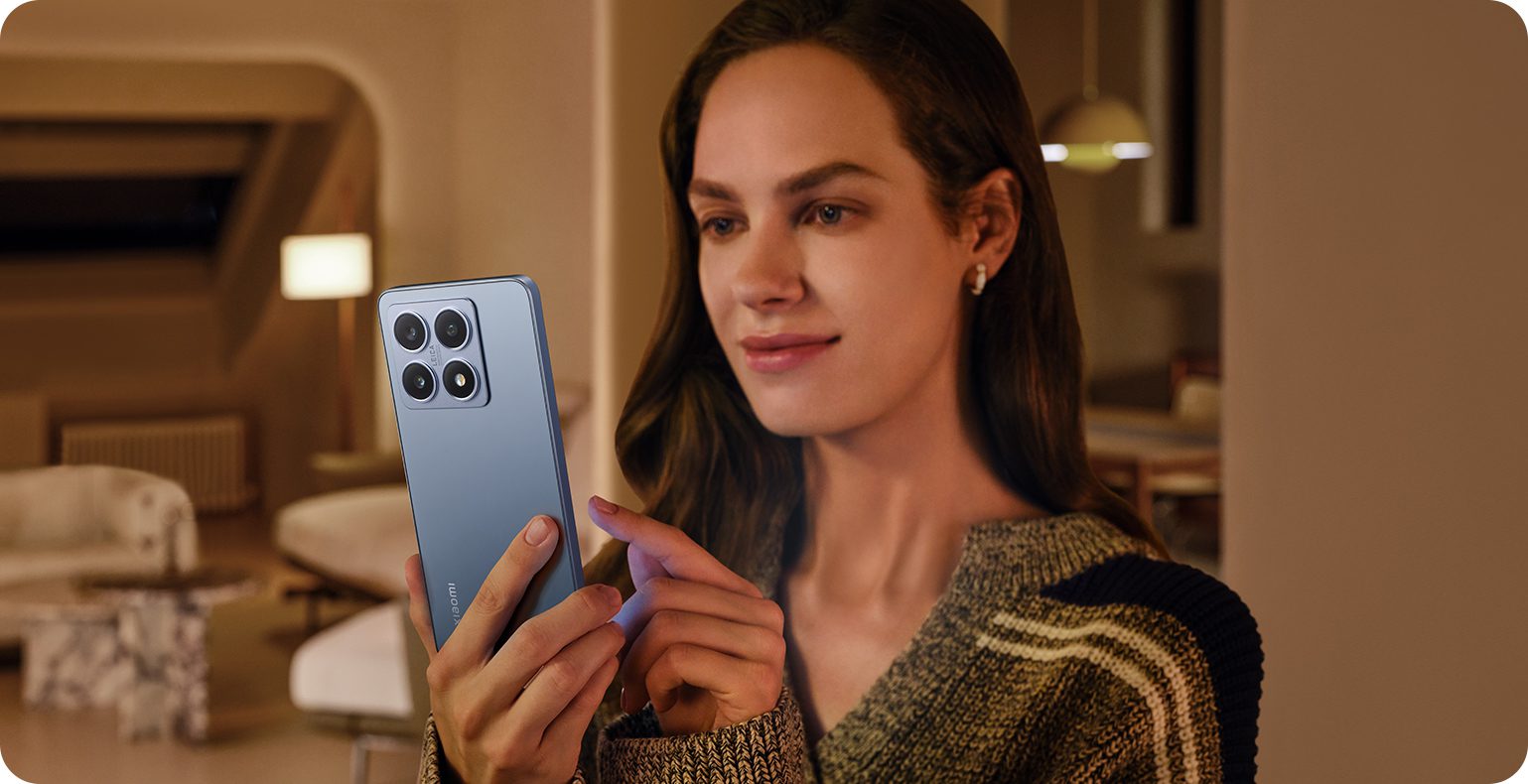 استفاده از گوشی Xiaomi 14T 5G آبی توسط کاربر در فضای داخلی با نور گرم