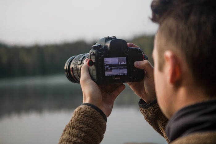 نمای نزدیک عکاسی که هیستوگرام دوربین DSLR خود را می خواند