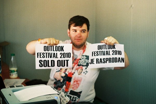 مردی چاق که دو تکه کاغذ در دست دارد و می گوید: جشنواره Outlook 2010 تمام شد