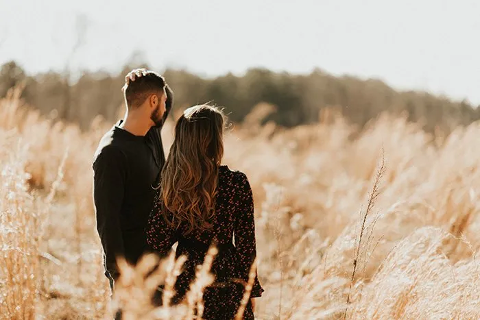 ژست عاشقانه زن و شوهر در دشت با نگاه به دوردست برای عکاسی طبیعی