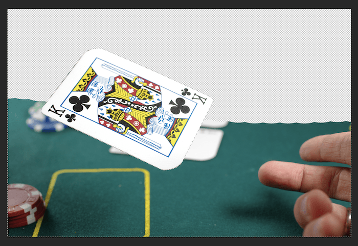 عکسی از یک کارت بازی که روی میز انداخته می شود و نیمی از پس زمینه آن در فتوشاپ پاک شده است.