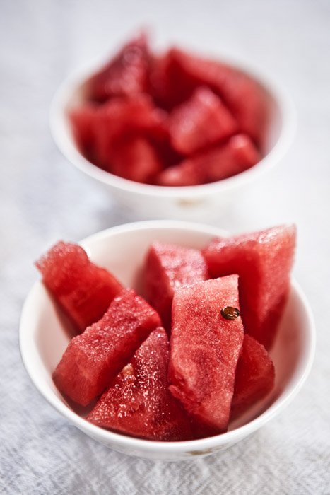 Two bowls of chopped watermelon, the background out of focus to demonstrate focal weight balance in photography