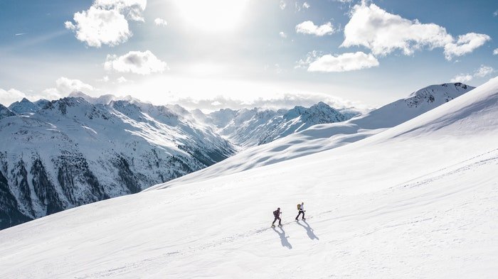 دو کوهنورد در حال راه رفتن روی کوهی با وزن بصری متعادل کوه ها در پس زمینه