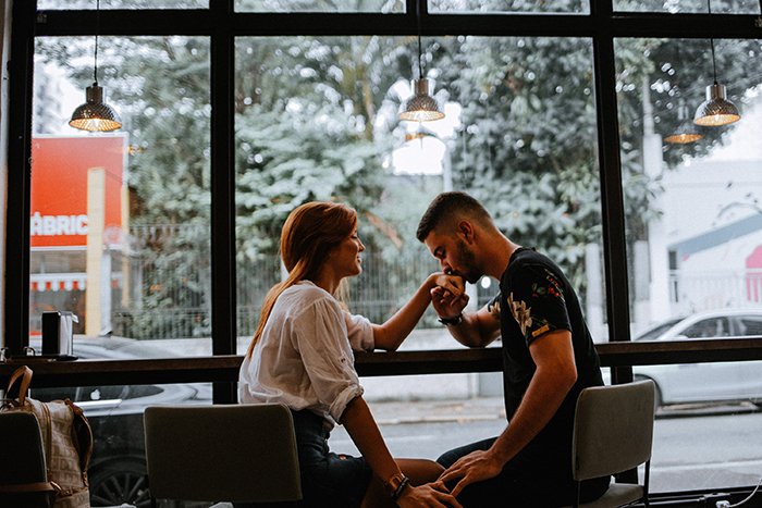 مردی در حال بوسیدن دست همسرش در کافه