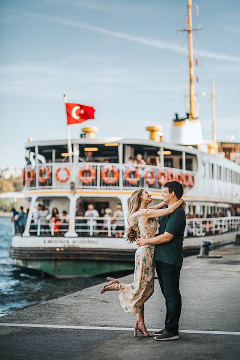 زن و شوهری که در اسکله مقابل یک قایق بزرگ در آغوش گرفته اند