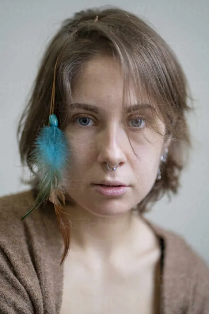 زن جوان با استایل هیپستر و پر رنگی در مو در حال نگاه به دوربین