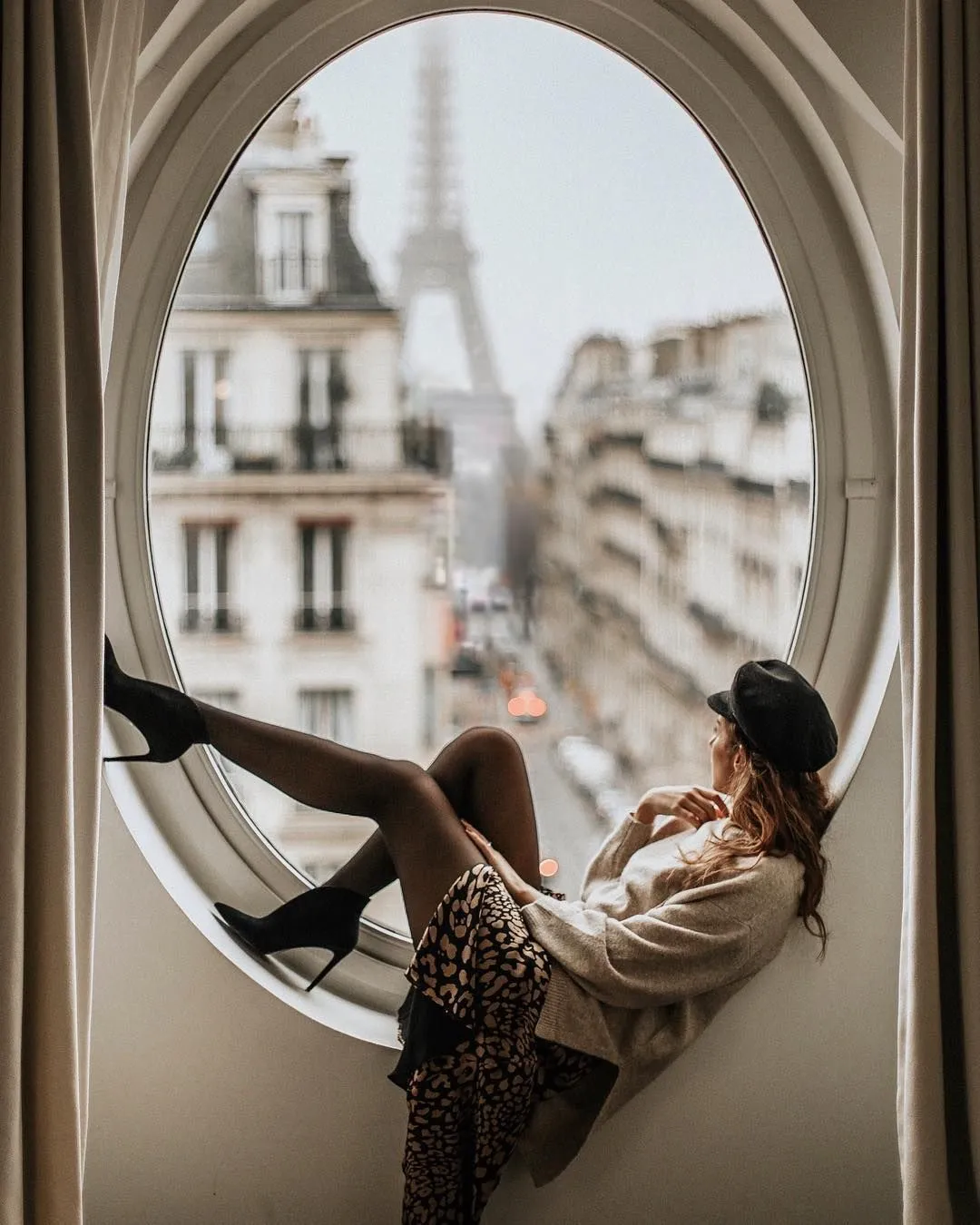 پرتره دختر روی قاب پنجره با نمای برج ایفل در پسزمینه