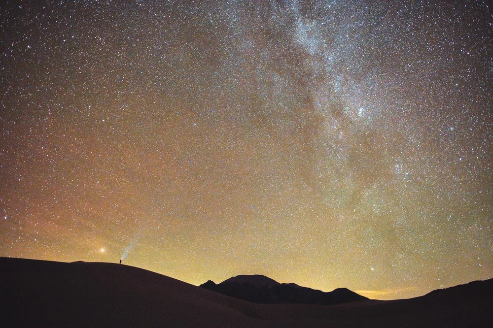 Milky Way with a tiny human in the foreground opt