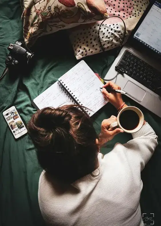 دختر در حال کار با لپتاپ و نوشتن یادداشت با فنجان قهوه