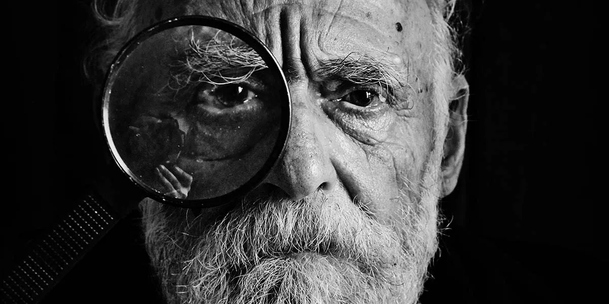 old man portrait with magnifying glass close up shot