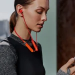زن جوانی در حال استفاده از هدفون بلوتوثی CMF مدل Neckband Pro با طراحی دورگردنی خاکستری، حذف نویز فعال و ظاهری شیک و راحت