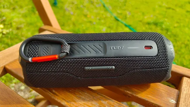 اسپیکر JBL Flip 7 مشکی روی صندلی چوبی در طبیعت