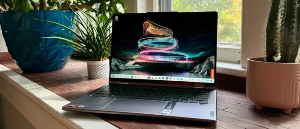 لپ‌تاپ Lenovo Yoga روی لبه پنجره با گیاهان گلدانی در کنار آن.